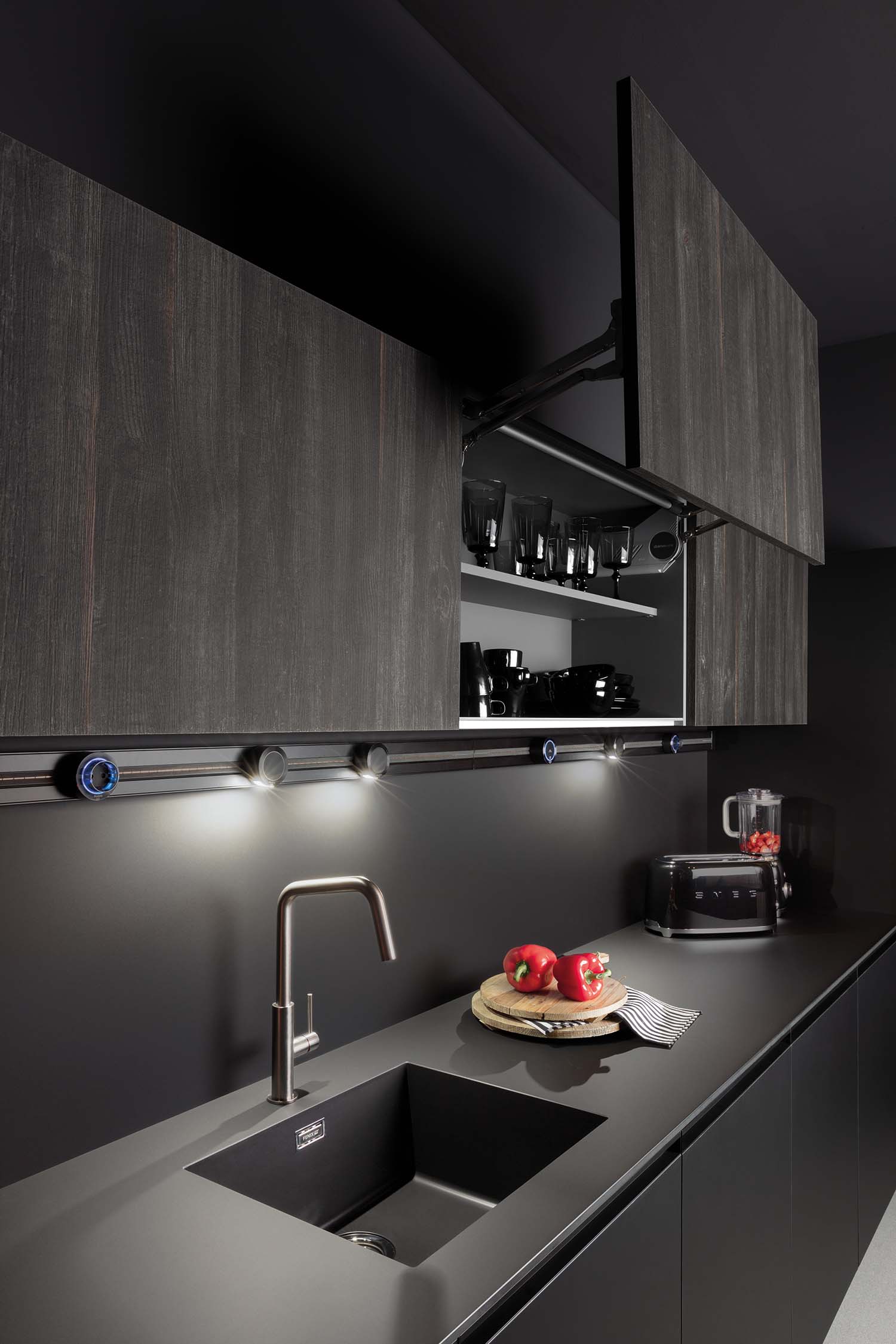 Vertically lifting push-pull operated kitchen wall units, finished in elegant dark wood veneer.